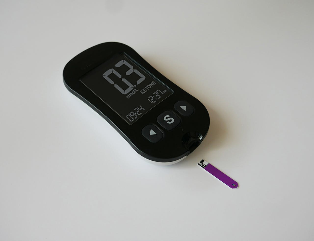 A close-up of a digital ketone meter on a plain surface, ideal for health tracking imagery.