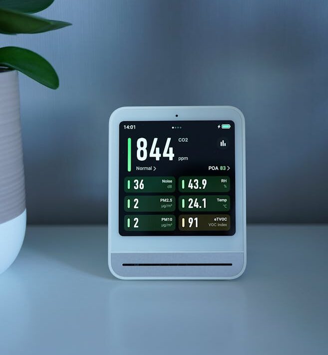 A sleek air quality monitor displays CO2 and particle levels, set on a modern desk indoors.